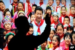 在北京展览馆前面，人们前往参观《砥砺奋进的五年》大型成就展里有中国主席习近平带着少先队的红领巾和少年儿童的合影（2017年10月23日）