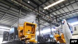 中国江苏省连云港市的一名工人在给工厂的机器喷洒消毒药水为工人节后返工做准备。（2020年2月9日）