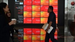 Para pengunjung melintas di depan layar yang menunjukkan data perdagangan Bursa Efek Indonesia (IDX), di Jakarta, 9 Maret 2020. (Foto: AFP)