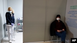 Seorang perawat berdiri di dalam bilik pusat vaksinasi COVID-19 "Promitheas Center", di Athena, Yunani, saat seorang pria menunggu untuk disuntik vaksin Moderna, Senin, 15 Februari 2021.