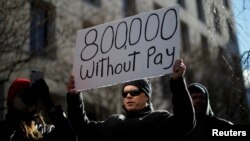 Seorang demonstran mengangkat papan bertuliskan "800 Ribu (Pegawai Federal) Tidak Gajian" akibat 'Shutdown' dalam aksi "Protes (untuk) Akhiri 'Shutdown'" di Washington, 10 Januari 2019.