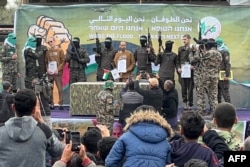 Palestinian Hamas fighters escort Israeli hostages Ohad Ben Ami, Eli Sharabi and Or Levy on a stage before handing them over to a Red Cross team in Deir el-Balah, central Gaza, Feb. 8, 2025.