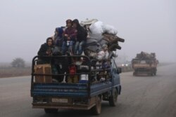FILE - Civilians ride in a truck as they flee Maaret al-Numan, Syria, ahead of a government offensive, Dec. 23, 2019. The M5 strategic highway is vital for Syria’s economy as well as for moving troops.