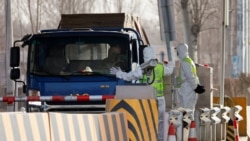 身穿防护服的警察在河北省通往北京的一个道路检查站拦住一辆卡车。（2021年1月12日）