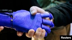 Čovek se rukuje sa robotskom rukom u izložbenom prostoru kompanije Intel na Međunarodnom sajmu potrošačke elektronike (CES) u Las Vegasu, Nevada, 6. januar, 2015. (Foto: REUTERS/Rick Wilking)