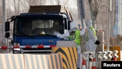 身穿防护服的警察在河北省通往北京的一个道路检查站拦住一辆卡车。（2021年1月12日）