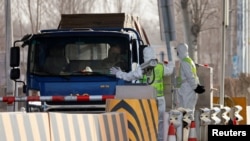 身穿防护服的警察在河北省通往北京的一个道路检查站拦住一辆卡车。(资料照, 2021年1月12日)