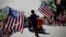 A boy carries American flags through Barnstable Village, Massachusetts, on Cape Cod during the annual Fourth of July Parade celebrating the country's Independence Day on July 4, 2024.