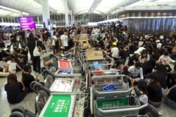 Protesters use luggage trolleys to block the walkway to the departure gates during a demonstration at the Airport in Hong Kong, Aug. 13, 2019.
