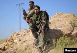 Fighters from the Syrian Democratic Forces hold walkie-talkies in the village of Baghuz, Deir el-Zour province, Syria, March 20, 2019.
