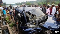 People look at the wreckage of a car following a road accident in Kinshasa, on February 16,
