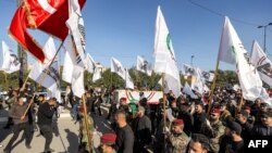 Anggota dari kelompok militan Syiah Kataib Hizbullah,membawa peti jenazah rekan mereka yang tewas dalam serangan AS, dalam prosesi pemakaman di Baghdad pada 26 Desember 2023. (Foto: AFP/Ahmad Al-Rubaye)