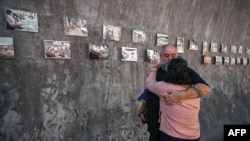 Les proches d'une victime du tsunami pleurent à côté de vieilles photos au mémorial du tsunami, Thaïlande, le 26 décembre 2024.
