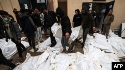 2023年12月25日，在加沙地带南部代尔巴拉赫的阿克萨医院举行集体葬礼之前，医务人员和志愿者摆放的在以色列袭击马加齐难民营时丧生人员的尸体。（法新社照片）