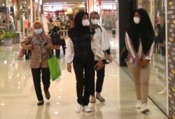 Sejumlah perempuan mengenakan masker sebagai pencegahan penyebaran virus corona berjalan di sebuah pusat perbelanjaan di Tangerang, Senin, 1 Maret 2021. (Foto: AP/Tatan Syuflana)