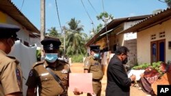 Hakim Sri Lanka Wasantha Ramanayake (kanan) dan polisi memeriksa suasana di luar sebuah rumah, tempat seorang gadis berusia sembilan tahun tewas di Delgoda, Sri Lanka, Minggu, 28 Februari 2021.