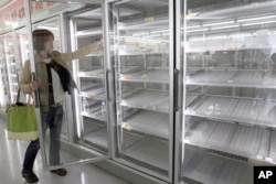 一女士从东京某便利店几乎空掉的货柜里拿出一瓶果汁