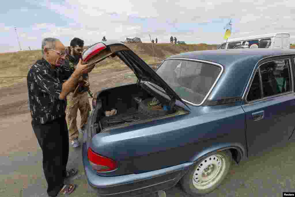 A man opens the trunk of a car for an &quot;Azov&quot; soldier at a checkpoint in Mariupol, Sept. 8, 2014.