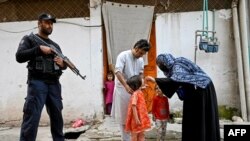 Seorang polisi khusus (kiri) berjaga sementara seorang petugas kesehatan (kanan) memberikan vaksinasi polio kepada seorang anak selama kampanye vaksinasi virus polio di pinggiran kota Peshawar, Pakistan (foto: dok).