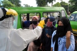Para penumpang angkutan umum mengenakan masker wajah sedang diperiksa suhu oleh petugas kesehatan di tengah penyebaran wabah virus corona (Covid-19), di Bogor, Jawa Barat, 8 April 2020.