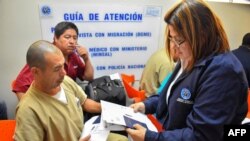 FILE - An immigration officer checks documents of a Salvadoran citizen deported from the U.S., at a Migrants Center in San Salvador, June 22, 2018.