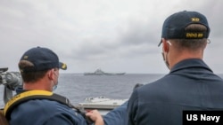 资料照片：美国海军公布的照片显示，两位美国海军中校罗伯特·J·布里格斯与理查德·D·斯莱2021年4月4日在阿利·伯克级导弹驱逐舰“马斯廷号”驾驶舱进行水面接触观察。照片中可见中国“辽宁号”航空母舰及其舷号。
