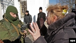 Ukraine -- A Ukrainian woman speaks with an armed man in military uniform, believed to be Russian soldiers, block the Ukrainian navy base in Novoozerniy village near of Feodosia, Crimea, March 3, 2014