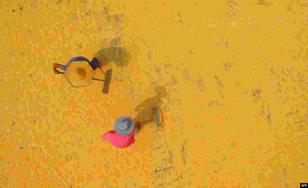 中国山东省临沂市郯城县，2018年8月30日，两位农民在收获季节晒玉米。中国玉米不能自给自足，需要进口。对美国玉米增加关税会抬高中国市场上的玉米价格，而不少玉米用于猪饲料，所以也会抬高猪肉价格。由美国国会成立的美中经济与安全审查委员会的报告说，在中美贸易战阴霾下，6月份美国对中国农产品出口与去年同比下跌34.4%。