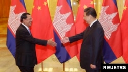 FILE: Cambodia's Prime Minister Hun Sen (L) stretches to shake hands with China's President Xi Jinping before a meeting at the Great Hall of the People in Beijing, November 7, 2014. REUTERS