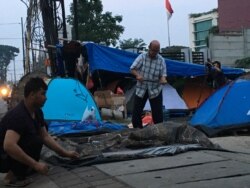 Saat pagi tiba para pengungsi dari Afghanistan melipat tenda yang dijadikan tempat tidurnya di depan rumah detensi imigrasi Jakarta .