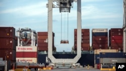 
在美国乔治亚州萨凡内港一架起重机正把一个集装箱装进一艘集装箱船上（2018年7月5日）
