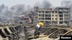 一名消防员站在损毁的汽车前。