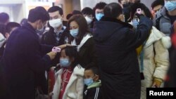 2020年1月23日杭州火车站工作人员检查从武汉到杭州乘客的体温。