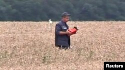 一个救援人员在马航飞机坠毁地点向同事展示记录飞行数据的黑匣子