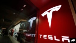 Sebuah tanda berlogo perusahaan ditampilkan di luar toko Tesla di Cherry Creek Mall di Denver. (Foto: AP)