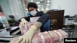 中国江苏省南通市一家银行的职员戴着口罩整理人民币钞票（2020年1月30日）