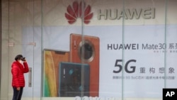 在北京一位女士站在华为手机的广告看板前(2020年3月8日)