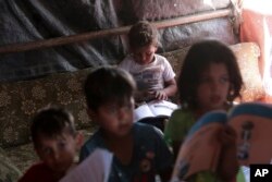 FILE - Syrian children read books in a refugee camp near Amman, Jordan, on June 5, 2023.