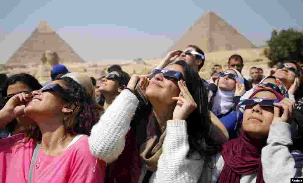 Orang-orang mengamati gerhana matahari sebagian di dekat Piramid Giza, di pinggiran Kairo, Mesir. Gerhana matahari total hanya dapat terlihat di Kepulauan Faroe dan&nbsp;​Svalbard di Norwegia.