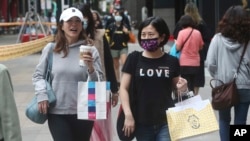 为防疫戴口罩的台湾民众走过台北的购物街区。（2020年10月29日）