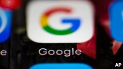 FILE- This April 26, 2017, file photo shows a Google icon on a mobile phone in Philadelphia. Google is spearheading an educational campaign to teach pre-teen children how to protect themselves from scams, predators and other trouble. The program announced Tuesday, June 6, is called “Be Internet Aware.” (AP Photo/Matt Rourke, File)