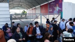 Warga Palestina yang memiliki dwi kewarganegaraan berkumpul di luar penyeberangan perbatasan Rafah dengan Mesir berharap mendapat izin keluar dari Gaza di tengah meningkatnya konflik Israel-Palestina, Sabtu, 14 Oktober 2023. (Foto: Ibraheem Abu Mustafa/Reuters)