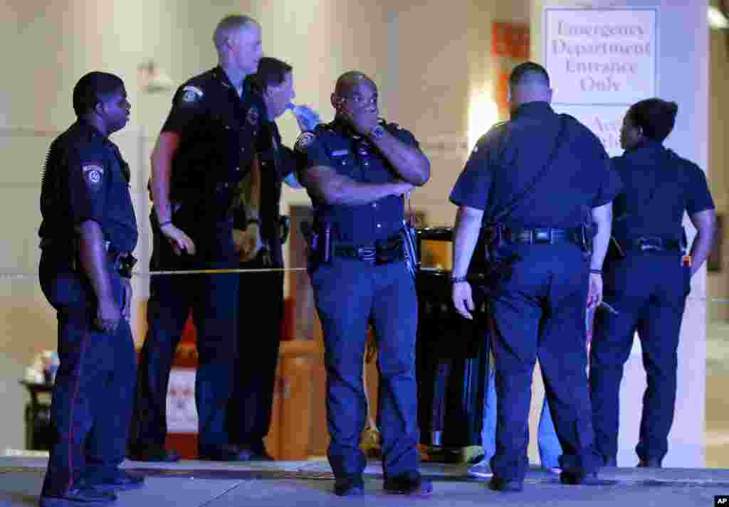 A Dallas police officer covers his face as he stands with others outside the emergency room at Baylor University Medical Center, July 8, 2016.