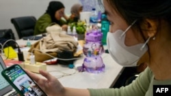 Seorang konsumen sedang memperhatikan live-streaming di TikTok oleh penjual yang menawarkan barangnya, di Jakarta, 4 April 2023. (Foto: Bay Ismoyo/AFP)