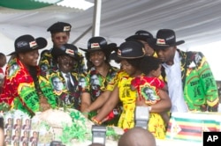 FILE - Zimbabwean President Robert Mugabe, center left, and his wife Grace, center are joined by his family as they cut the cake during his 93rd Birthday celebrations in Matopos on the outskirts of Bulawayo, Feb. 25, 2017.