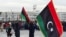Des Libyens brandissent le drapeau national sur la place des Martyrs à Tripoli, le 17 février 2025, lors d'un rassemblement pour commémorer le 14e anniversaire du soulèvement qui a renversé Mouammar Kadhafi, l'homme fort de longue date. (Photo par AFP)