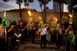 FILE - Protesters chant "Justice" as they carry images of slain journalist Javier Valdez Cárdenas during a demonstration outside the Interior Ministry in Mexico City, May 16, 2017.