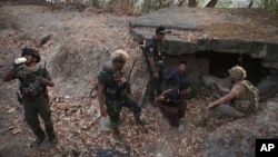 克伦民族解放军和人民防卫军成员在占领克伦邦妙瓦底镇南部一个政府军前哨后对两名被俘士兵进行检查。（2024年3月11日）