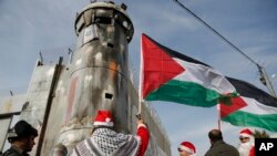 Palestinians dressed as Santa Claus confront Israeli border police during a protest in the West Bank city of Bethlehem, Dec. 23, 2017.