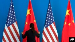 A Chinese woman adjusts the Chinese national flag near U.S. national flags, file photo. 